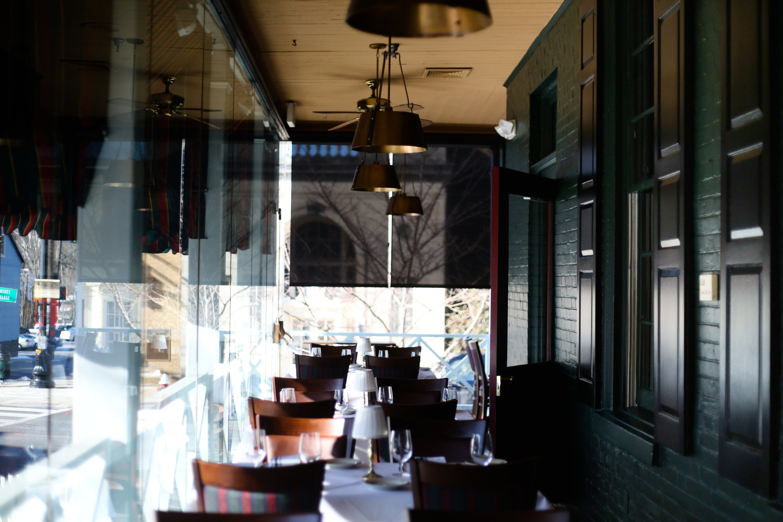 A restaurant with tables and chairs outside of the windows.