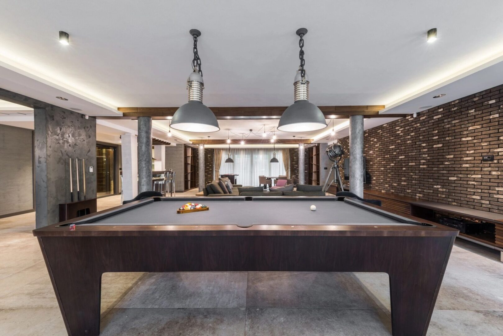 A pool table in the middle of a room with lights above it.