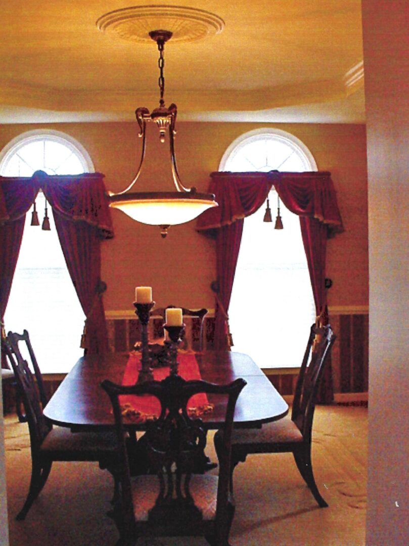 A dining room table with candles and red napkins.